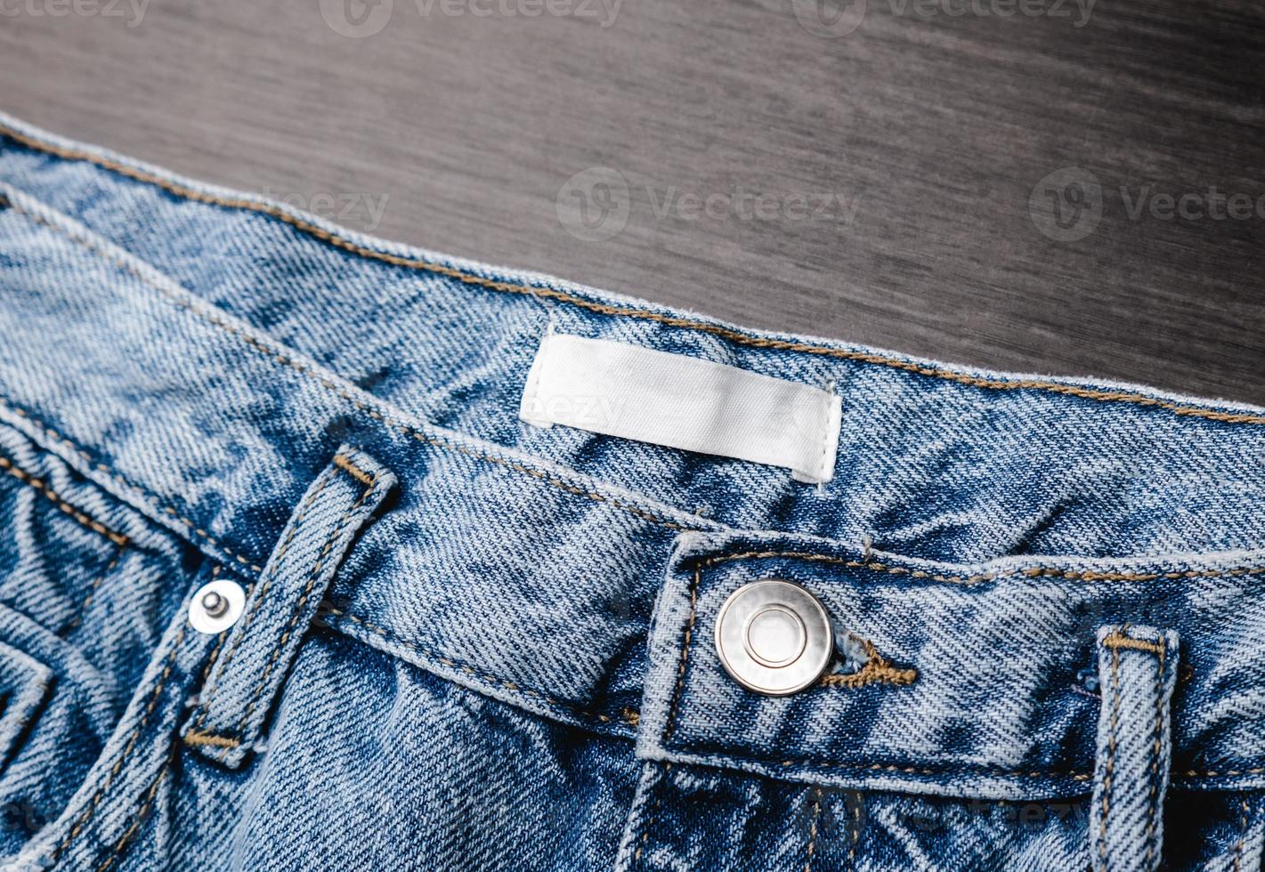 Blank clothing label on denim jeans texture. Label with empty space for text photo