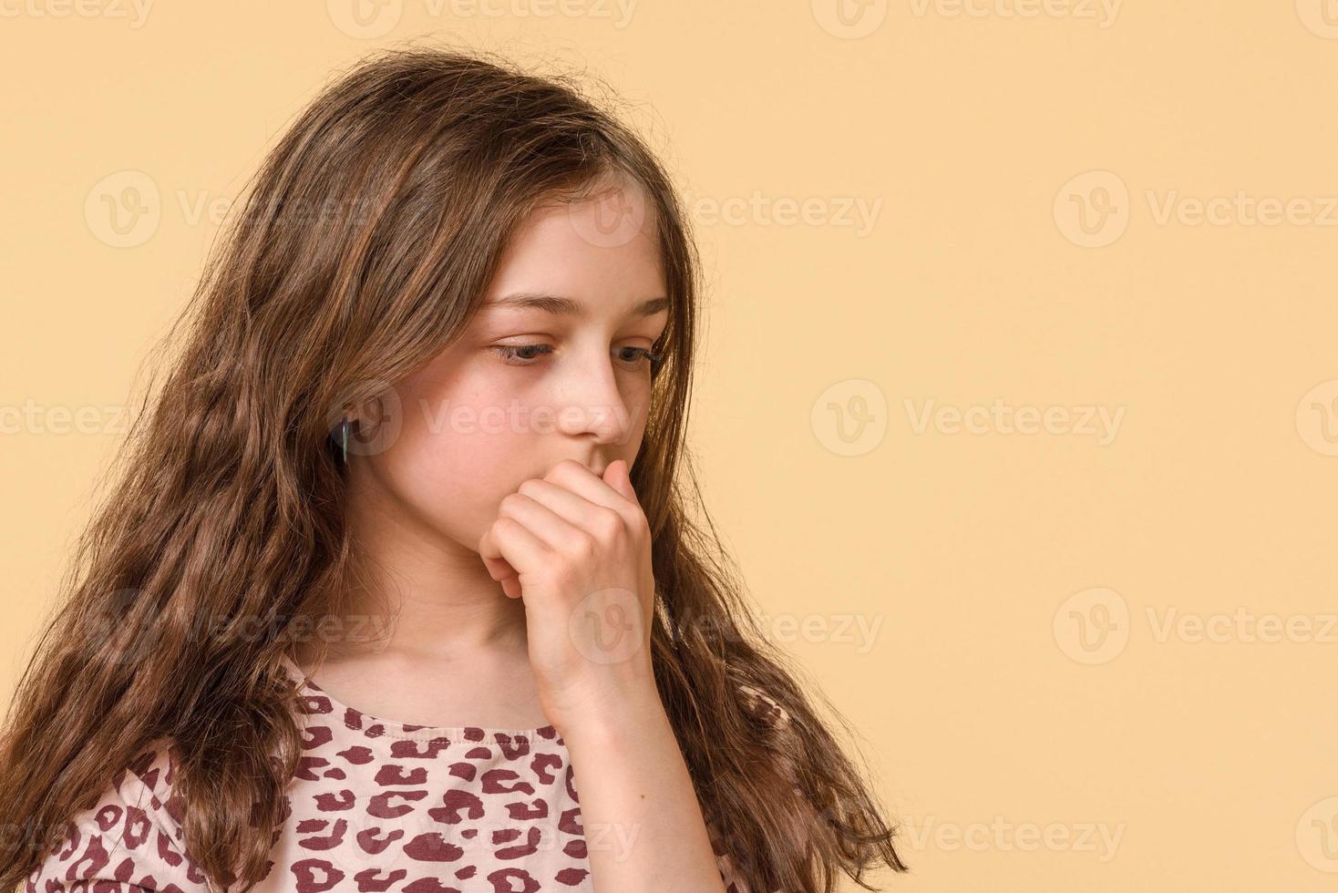 Teen girl pensive on a beige background. Adolescence, thoughts. photo