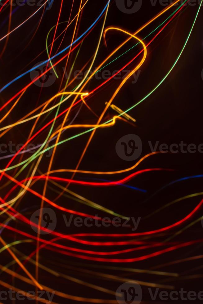 Drawing with light. Abstract multicolored rays on a black background. Curved wave lines. photo