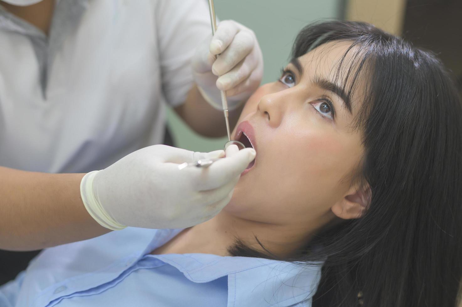 mujer joven con dientes examinados por dentista en clínica dental, revisión de dientes y concepto de dientes sanos foto