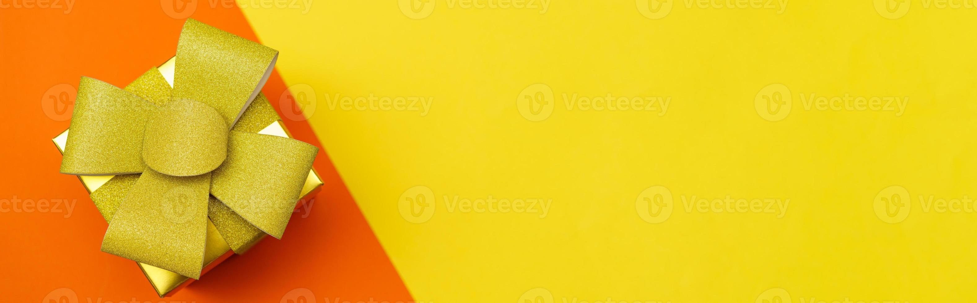 caja de regalo amarilla brillante con lazo dorado y cinta en amarillo y naranja foto