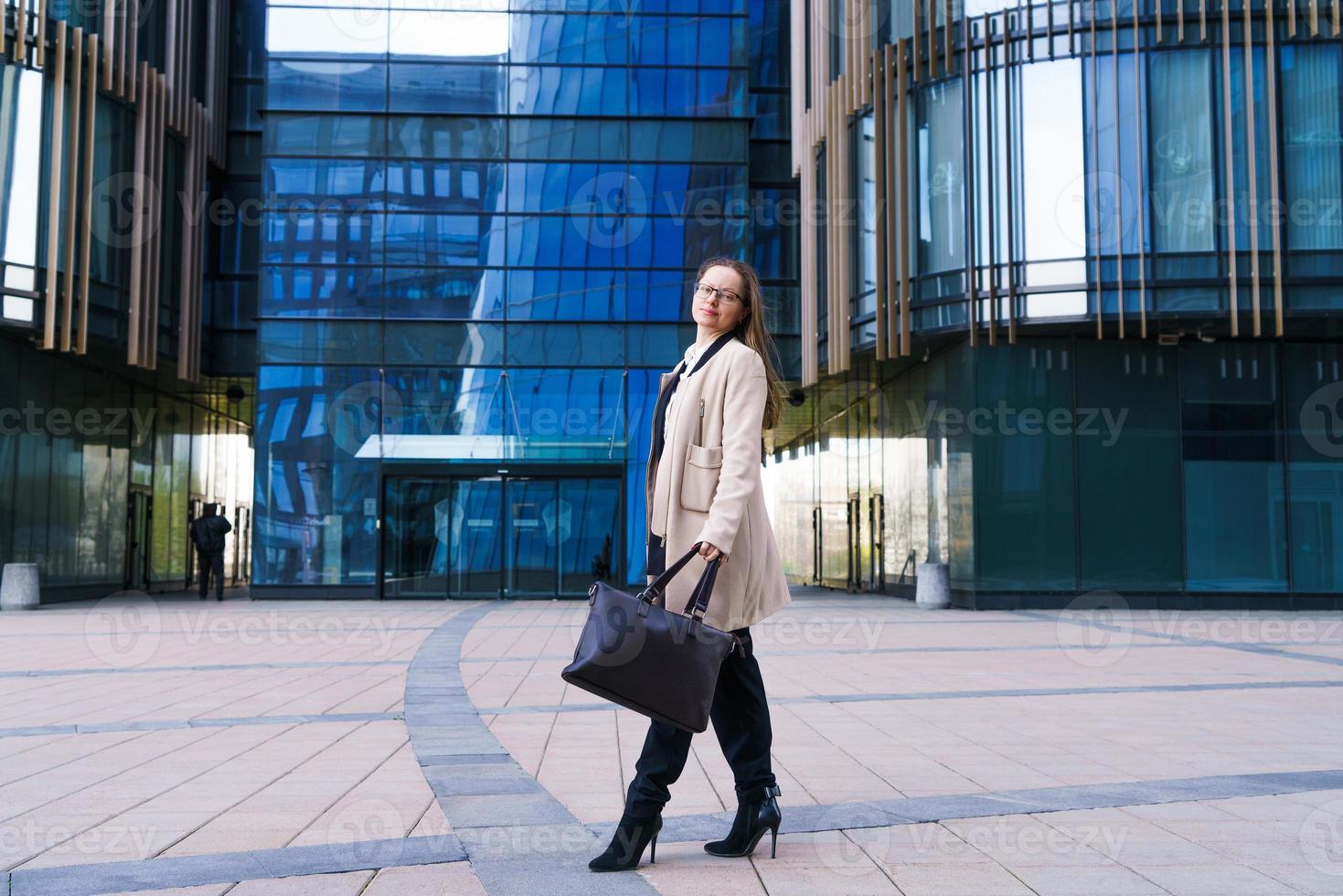 exitosa mujer de negocios feliz con bolsa sobre fondo de edificio de oficinas foto