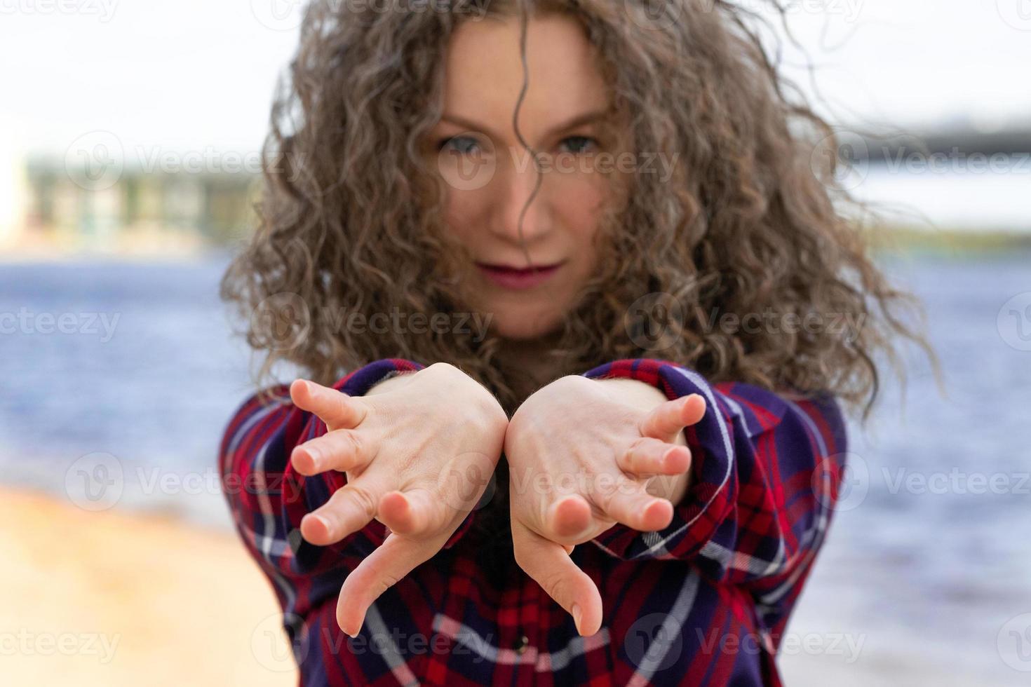 Close-up portrait of a woman dancing on the beach, hands in front of her in the frame photo