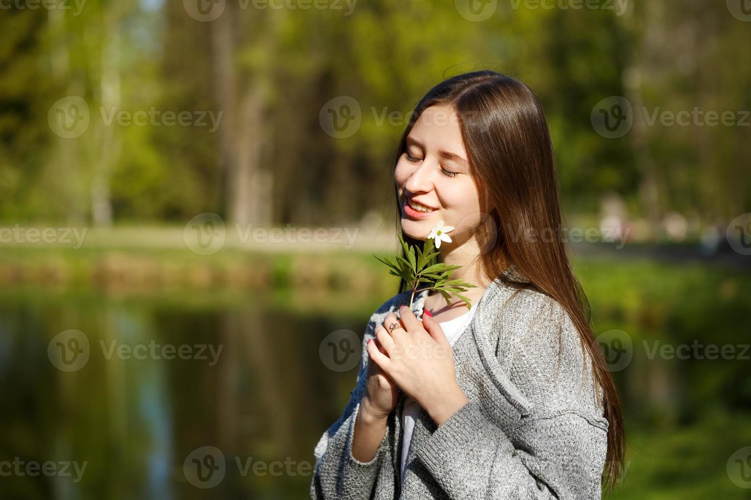 Portrait of a girl on the background of a Park with a lake, holding a wild forest flower. photo