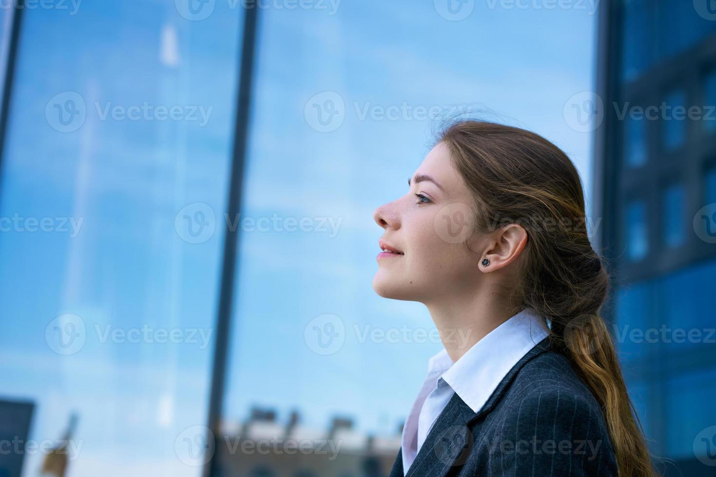 The girl stands sideways against the background of business centers. photo