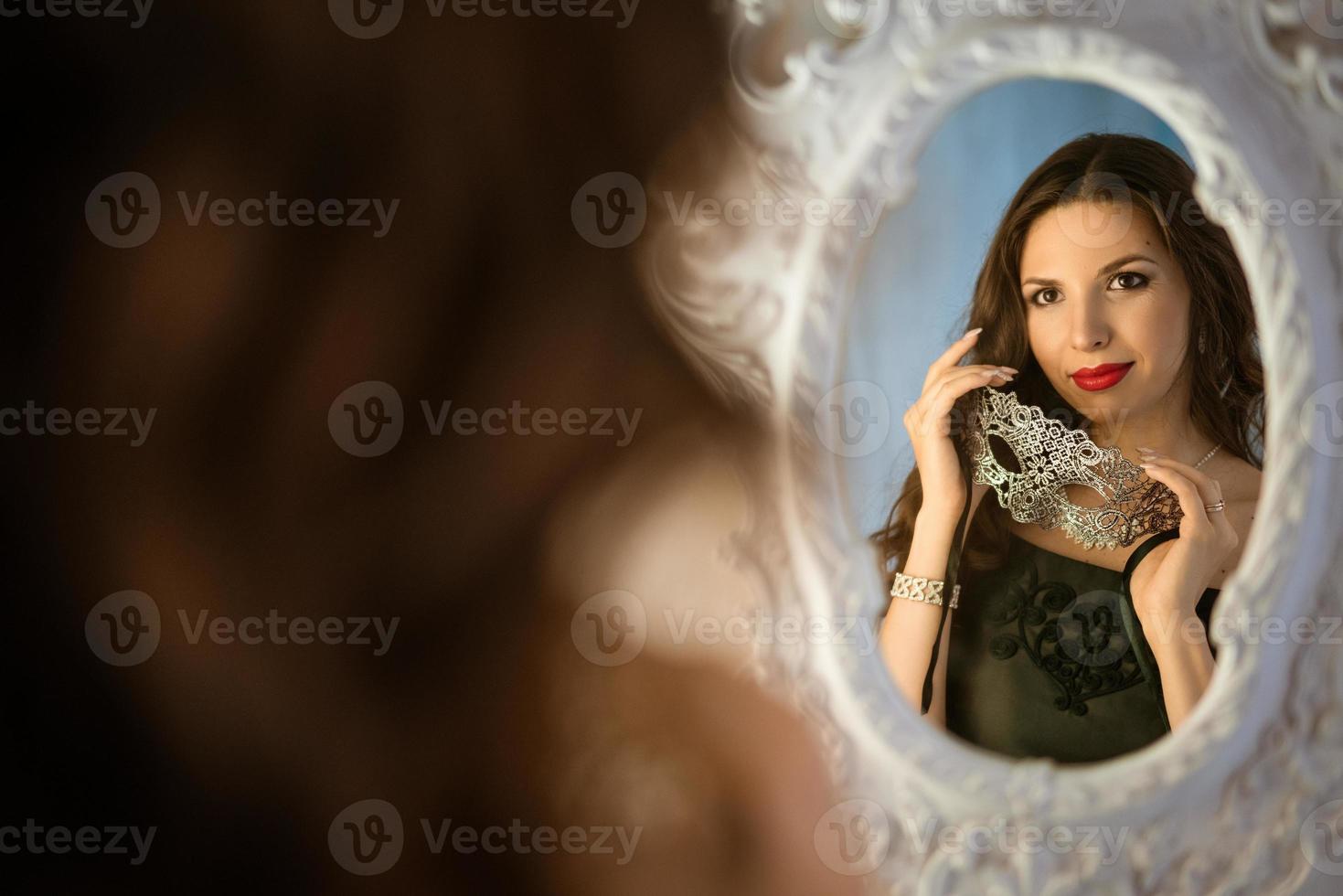 portrait of a beautiful woman with makeup with an openwork mask in her hand photo