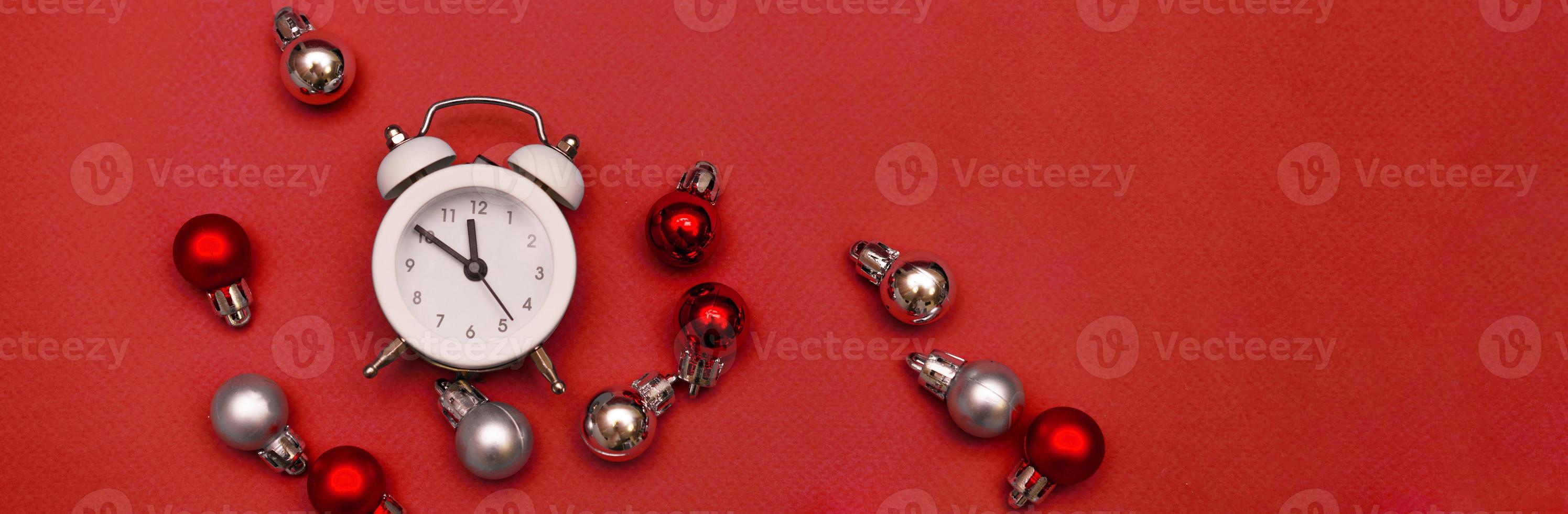 White alarm clock on red background with christmas balls photo