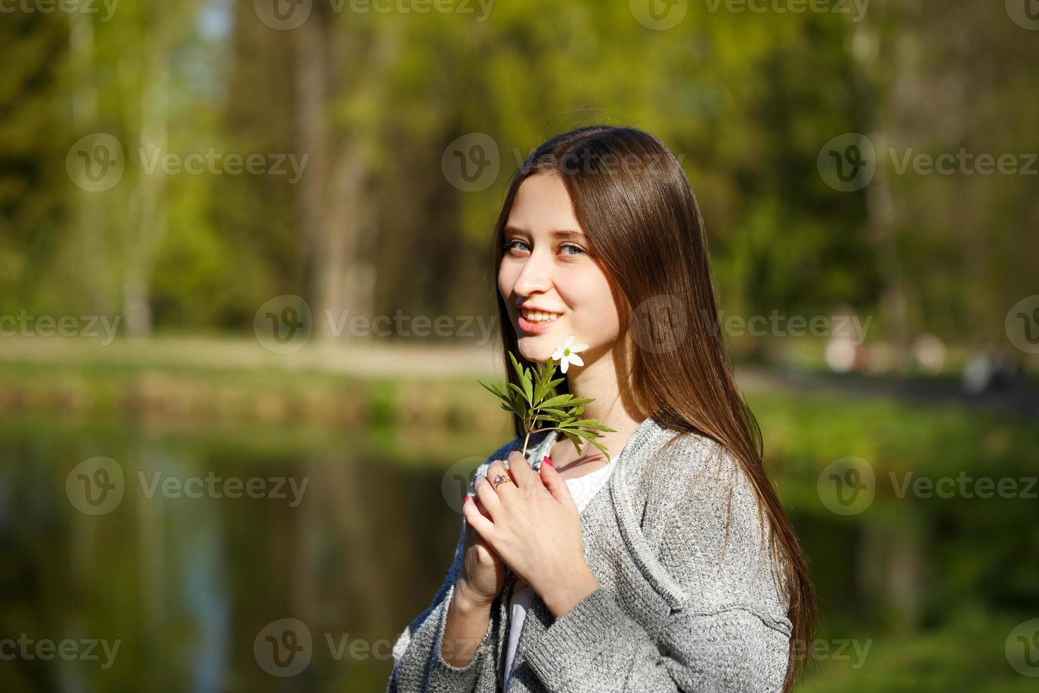 Portrait of a girl on the background of a Park with a lake, holding a wild forest flower. photo