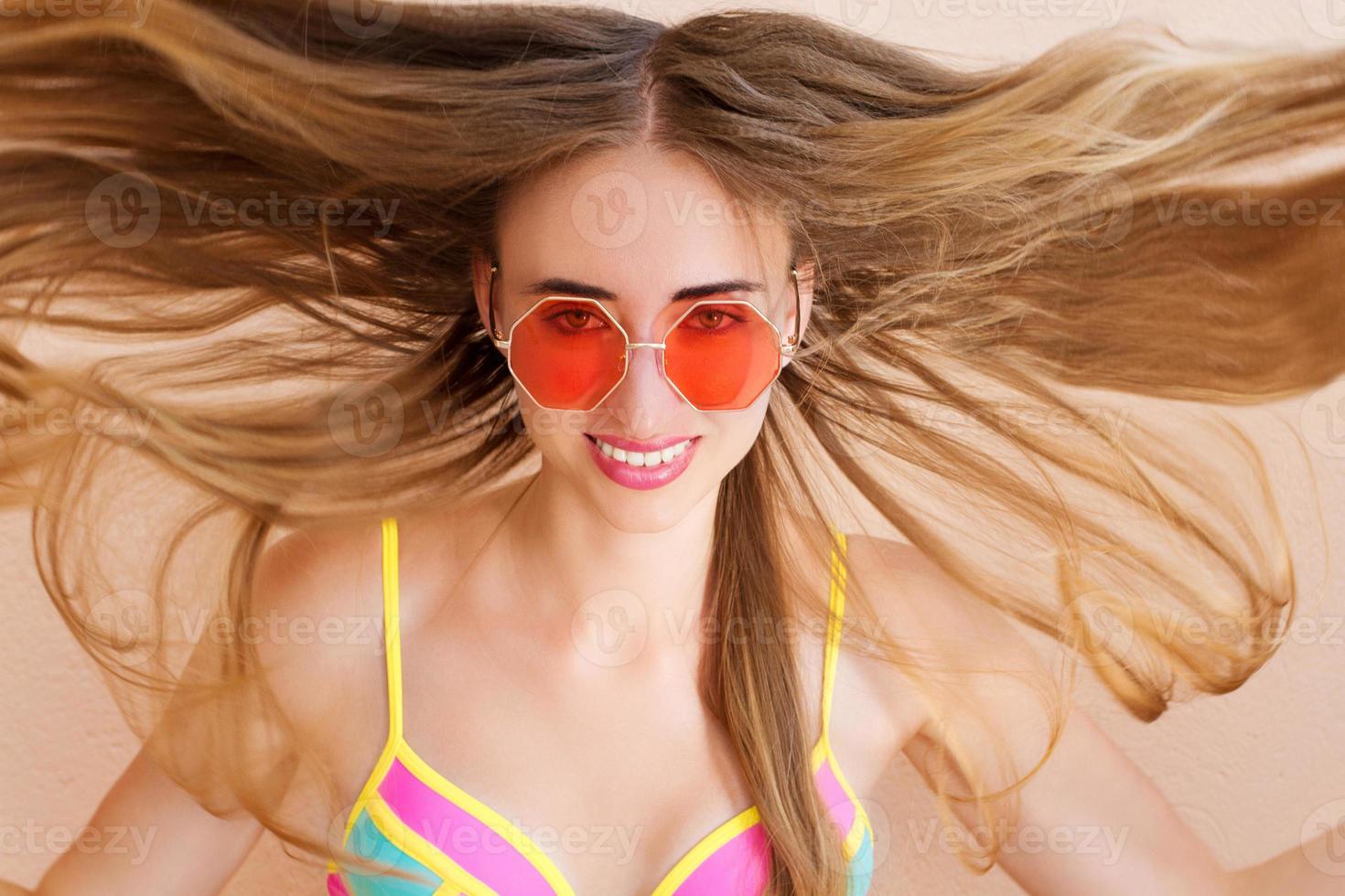 Close Up Of Happy Girl in pink sunglasses isolated. Summer holidays and fun time weekend. Summertime concept. Smiling young woman in fashion swimsuit. Selective focus. Beach Summer outfit style. photo