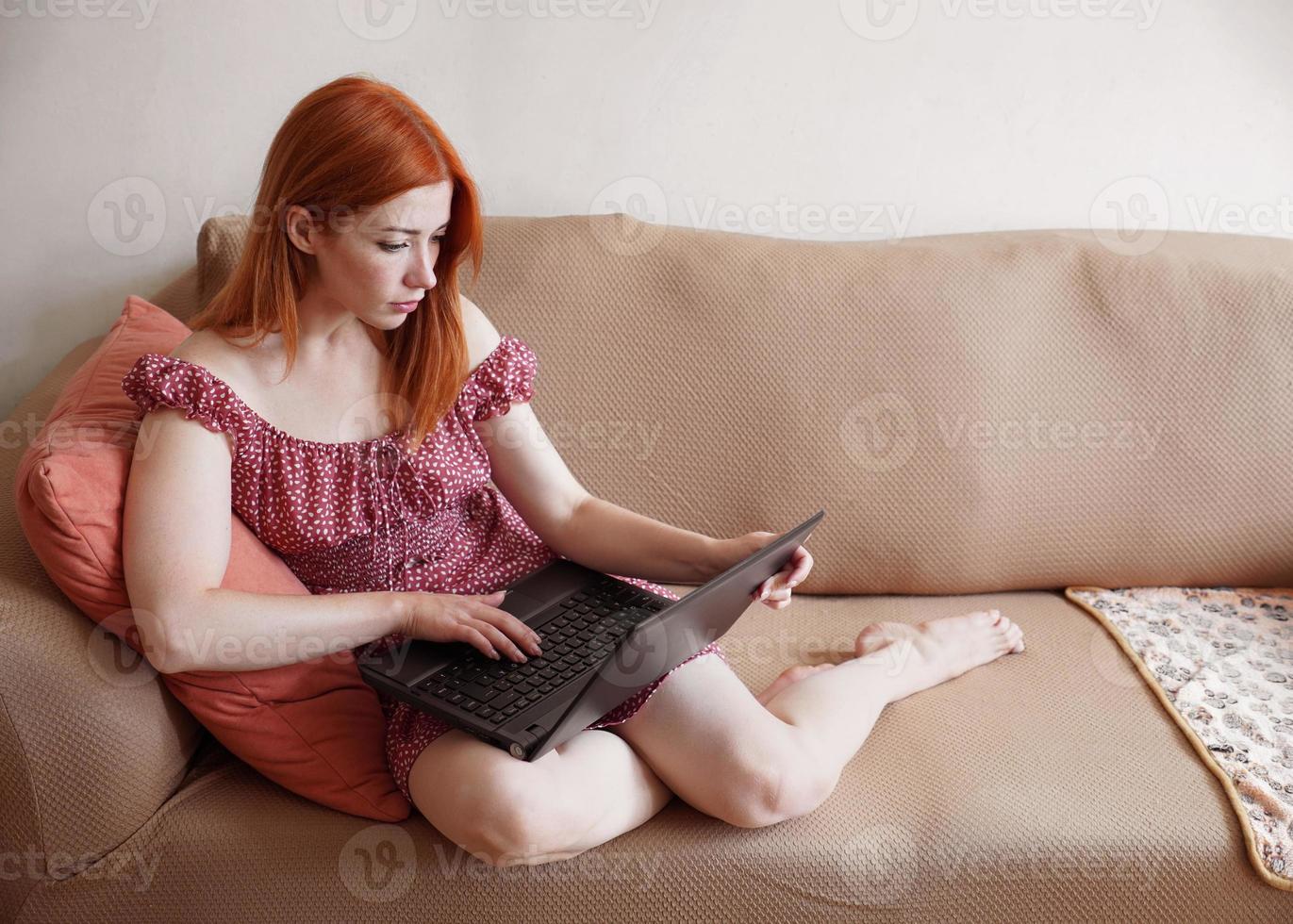 mujer usando computadora portátil en casa relajándose en el sofá foto