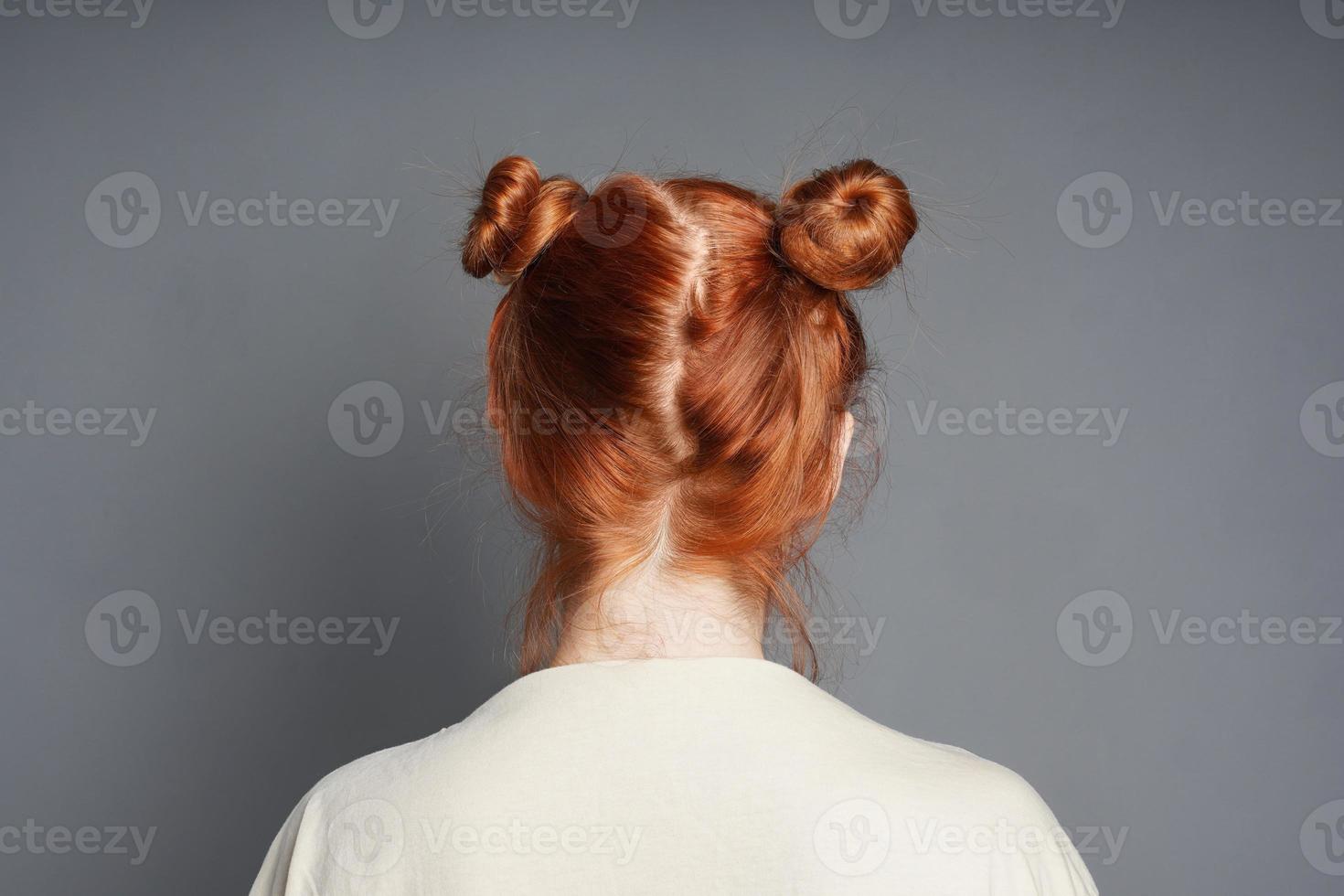 back view of red-haired woman with space buns hairstyle photo