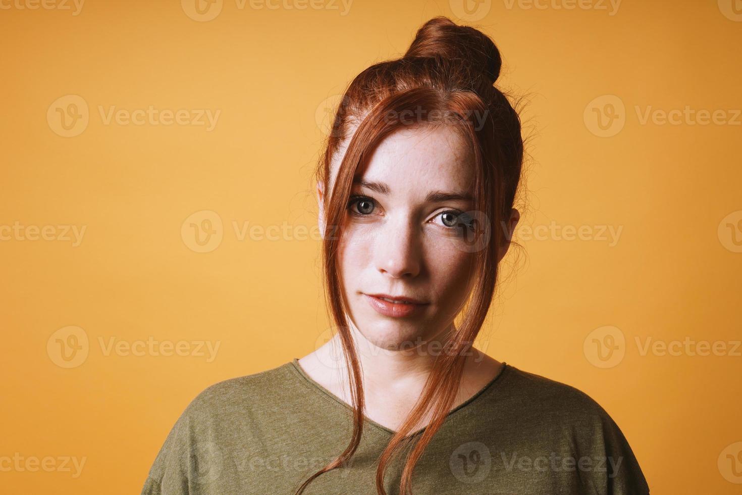 cool young woman with red hair messy bun hairstyle and loose strands photo