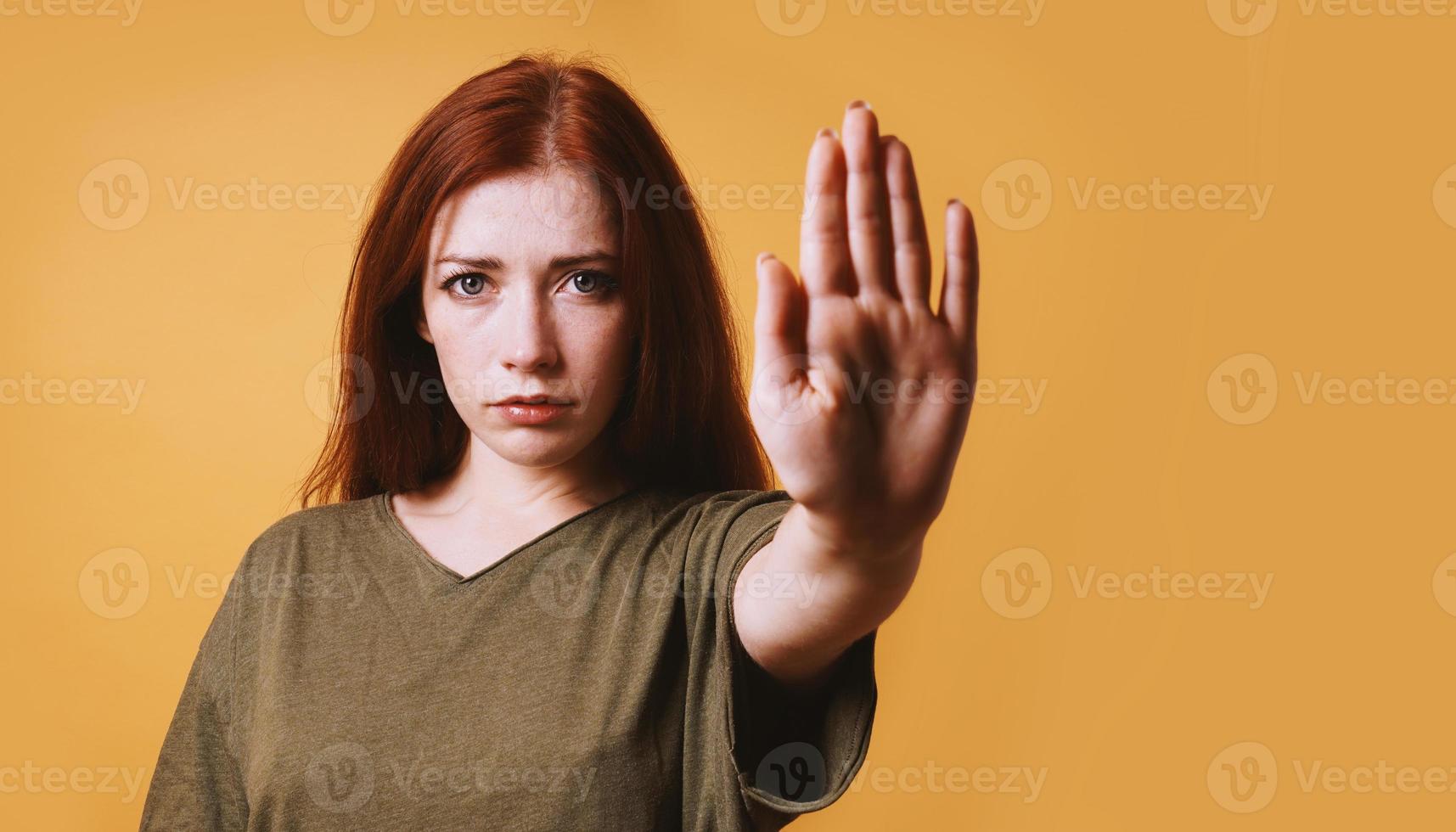 mujer joven seria que hace el gesto de la parada con la mano izquierda foto