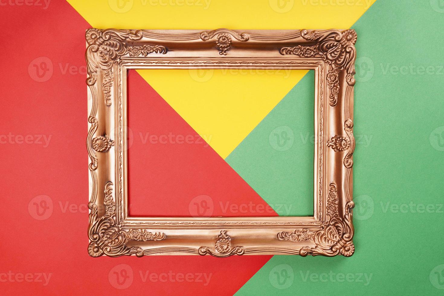 empty gold frame on color paper background in red green and yellow photo