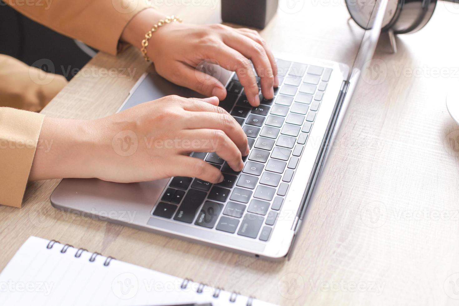 Hand of businessman or worker typing on a laptop keyboard with empty book and classic alarm clock photo