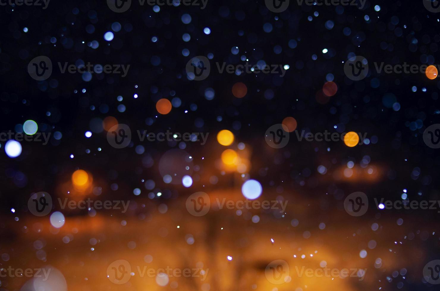 Nighttime falling snow with a bokeh effect against a background of city lights. photo