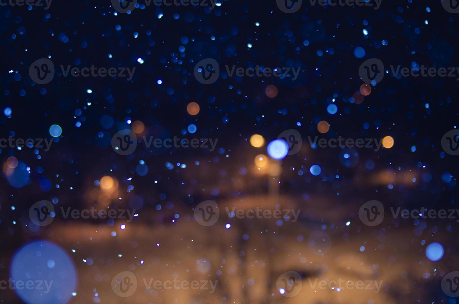 Nighttime falling snow with a bokeh effect against a background of city lights. photo