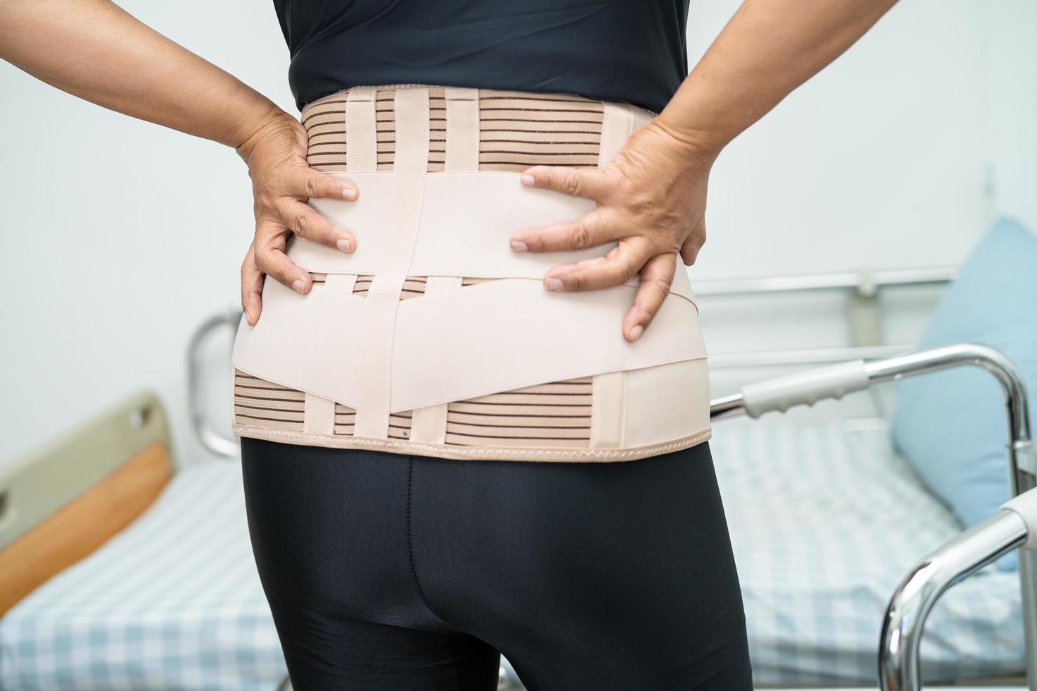 Asian lady patient wearing back pain support belt for orthopedic lumbar with walker. photo