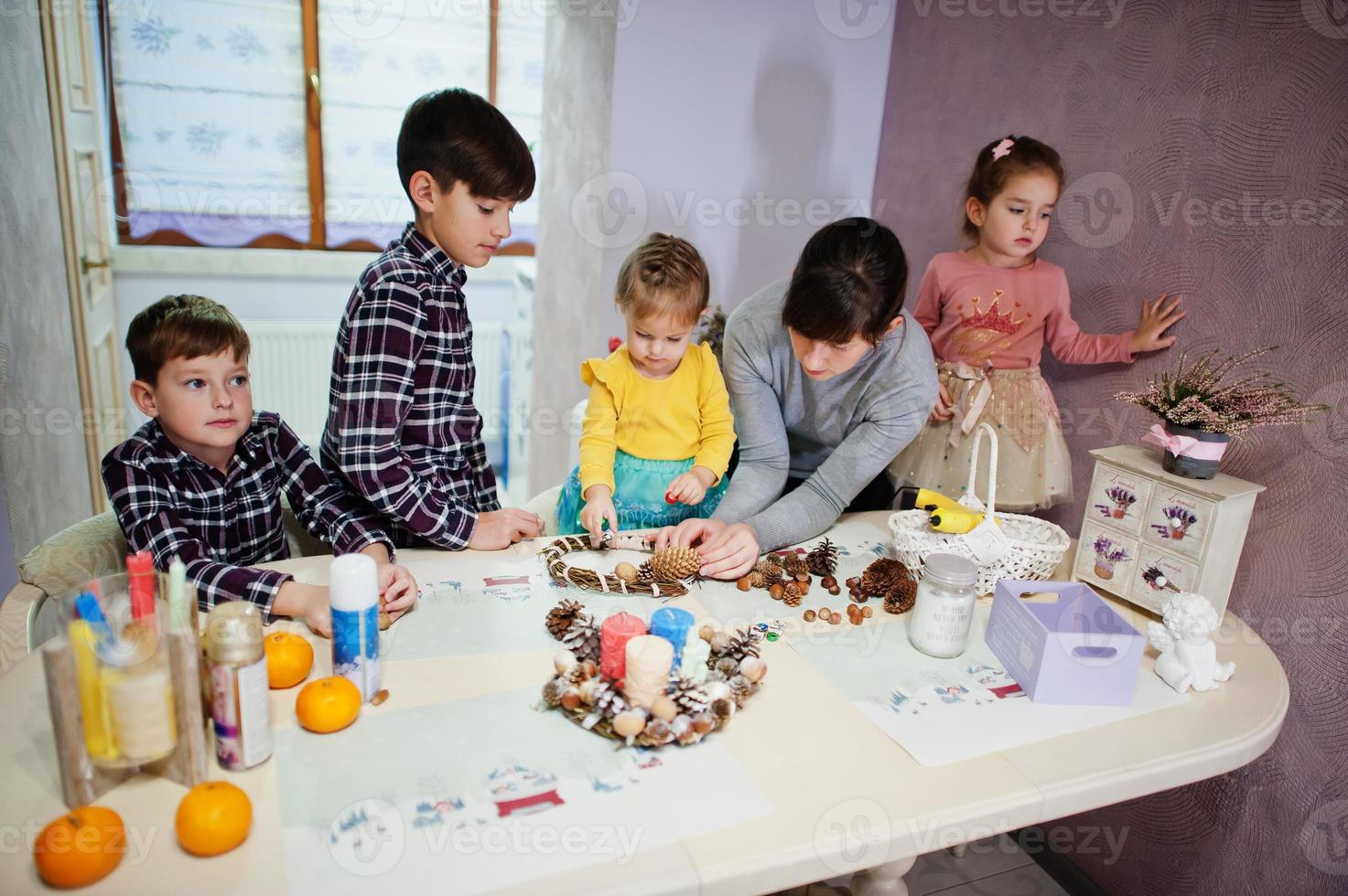 madre con cuatro hijos hace una corona para la víspera de navidad y la decoración artesanal. celebración de Año Nuevo. foto