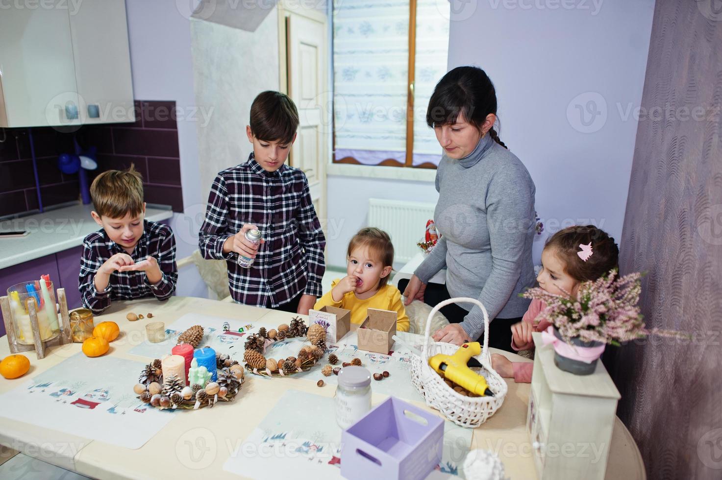 Mother with four kids makes a wreath for Christmas Eve and crafting decorating. New Year celebration. photo