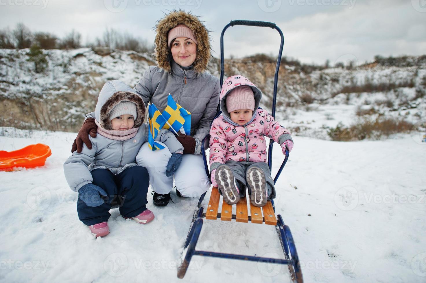 Mother with daughters hold Sweden flags in winter swedish landscape. photo