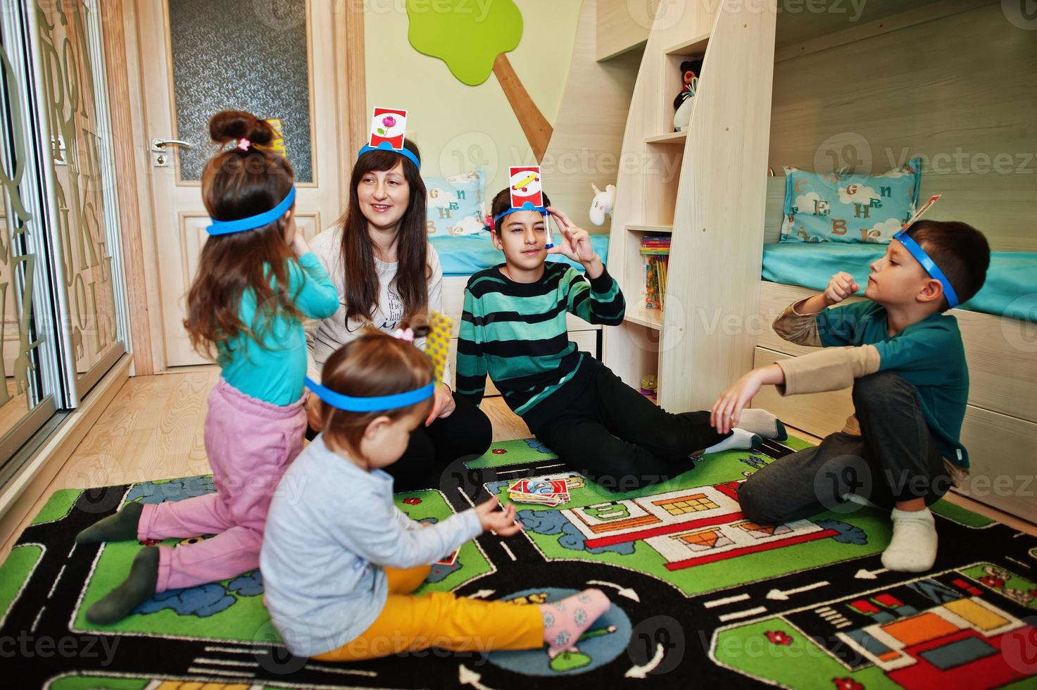 Happy family with four kids playing game guess who while having fun at home. photo