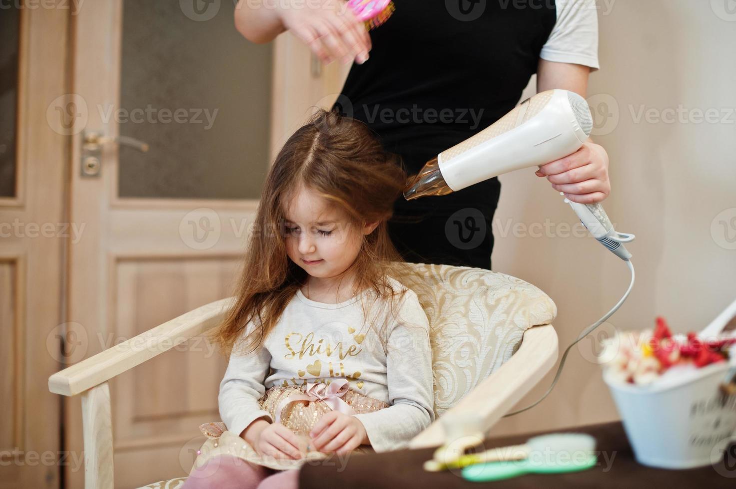 mamá con hija haciendo juntos la rutina diaria. la madre está cepillando y secando el cabello del niño después de la ducha. foto