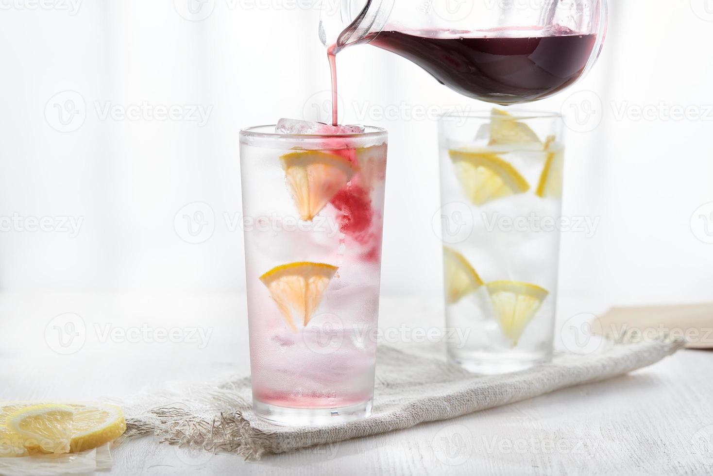 Two glasses of ice cold lemonade. Pour the syrup from the jug into the glass. photo
