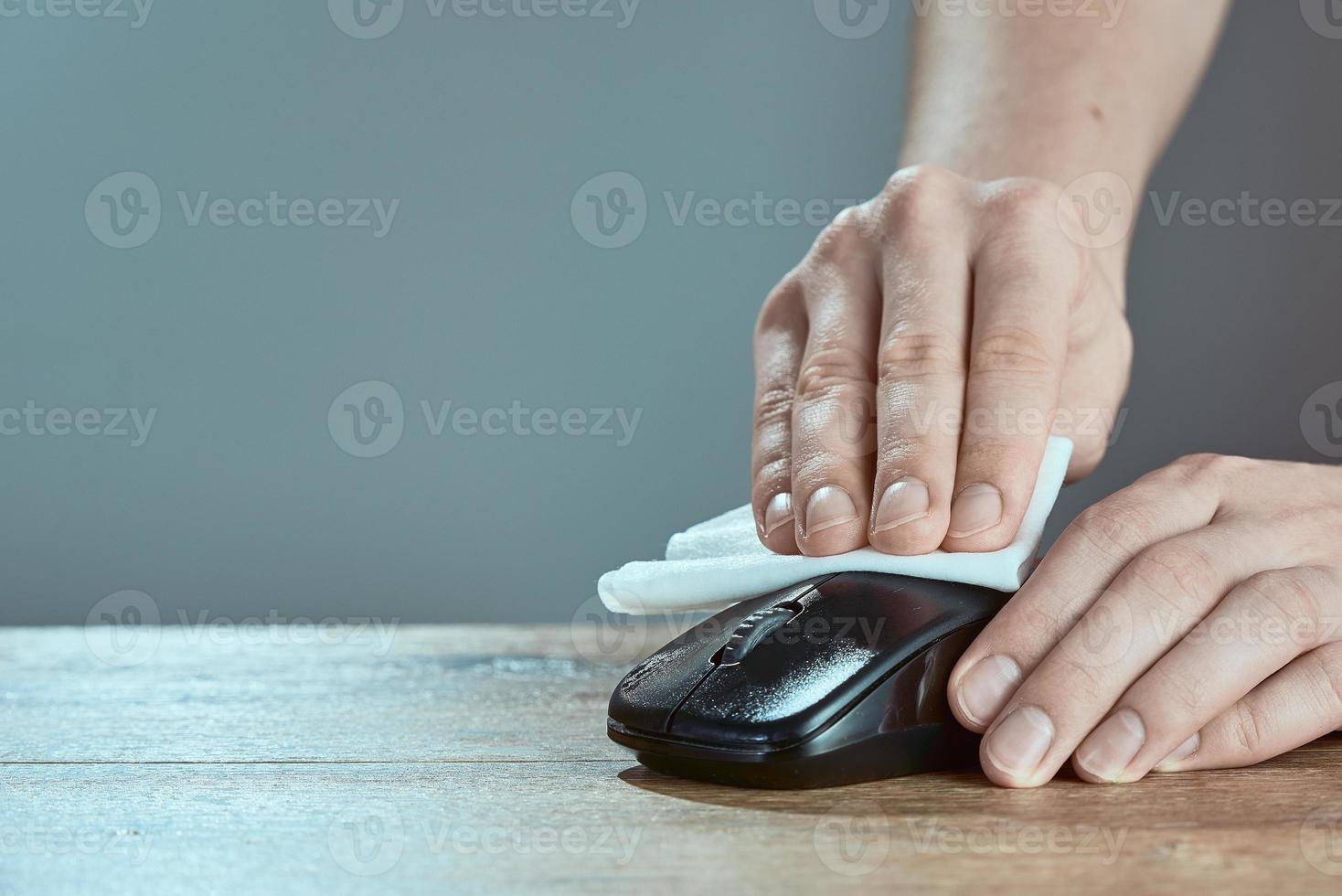 A man wipes mouse with napkin. Cleaning the computer mouse. photo