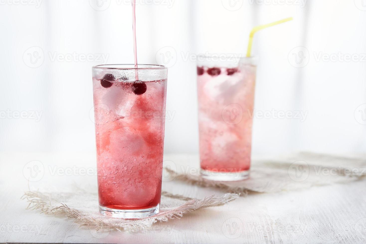 Two glasses of cold pink lemonade with blackcurrant berries on a white background in a blur. photo