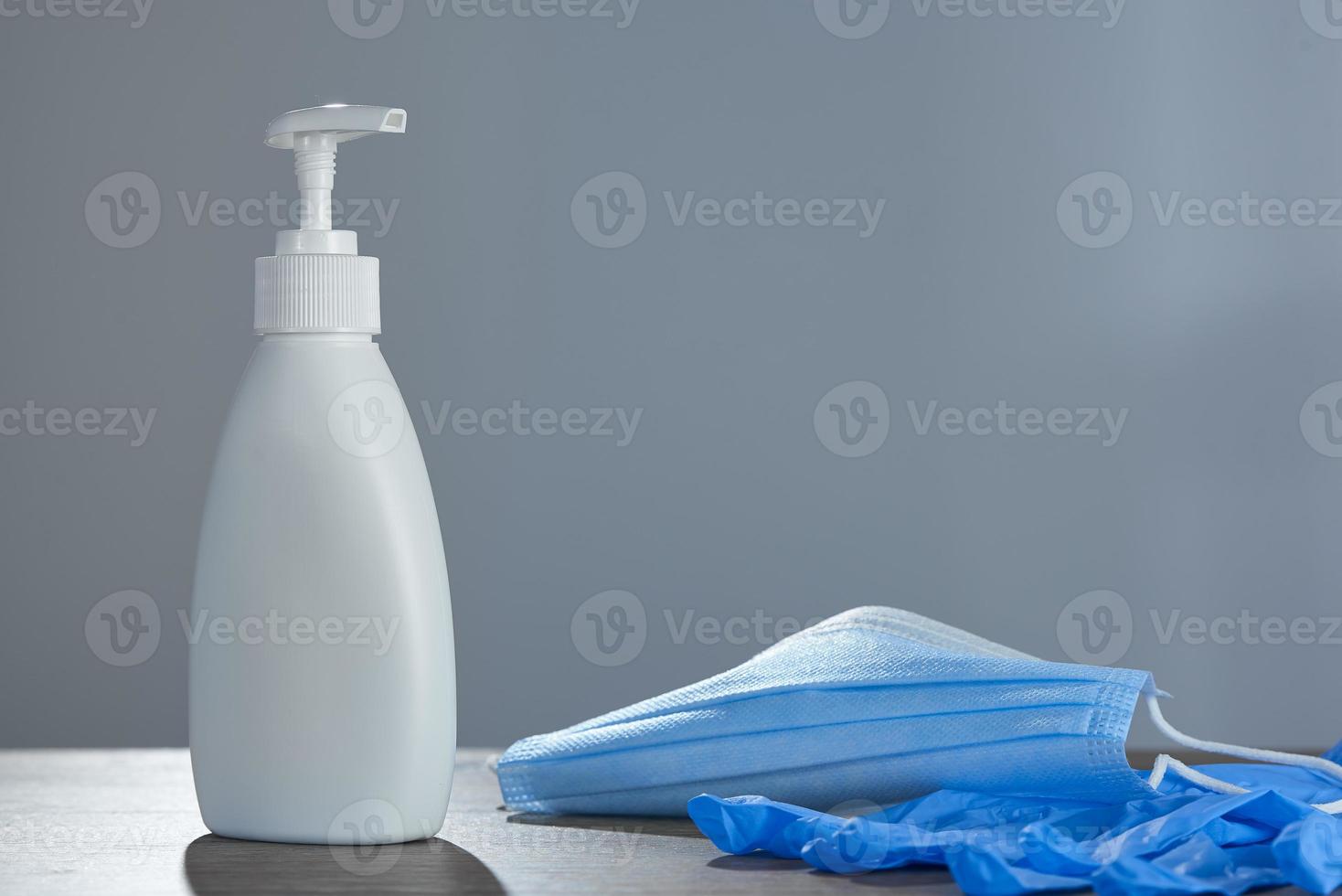 Prevention of coronavirus. A set of sanitizer, medical mask and rubber gloves on a gray background. photo