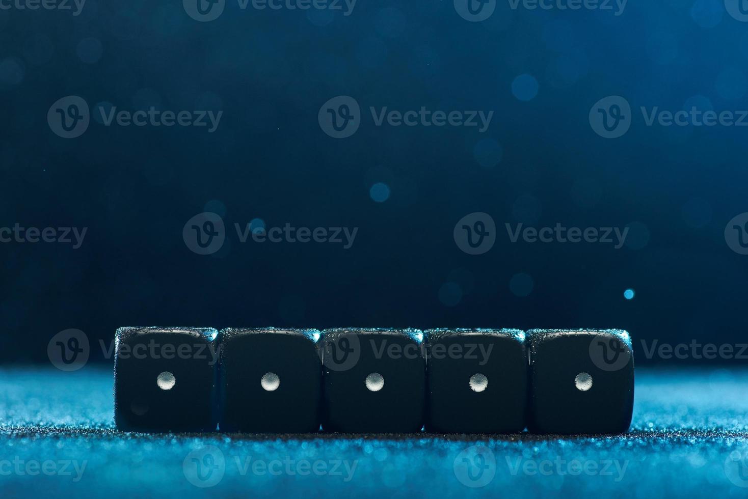 Game cubes are next to each other. Five identical black cubes on blue background. Photo with bokeh.