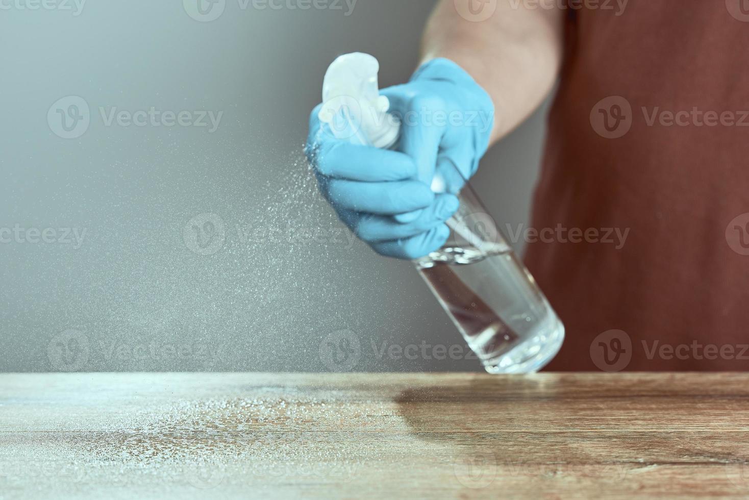 Hands in medical gloves treat the table with a sanitizer. The concept of cleaning. photo