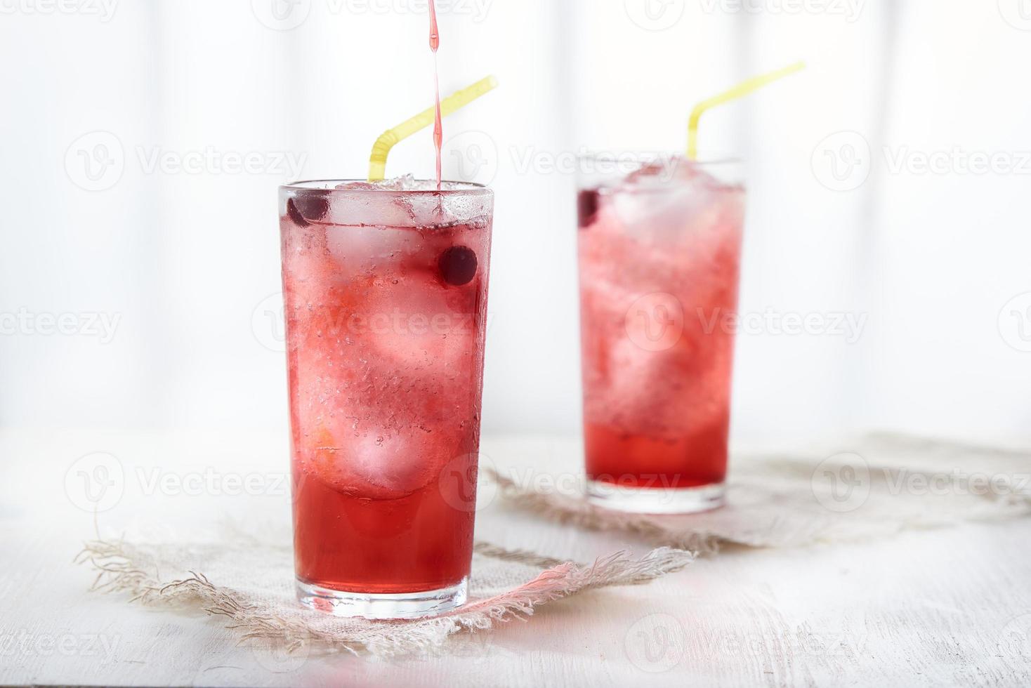 Two glasses of ice cold lemonade with blackcurrant berries . Pour the syrup into the glass. photo
