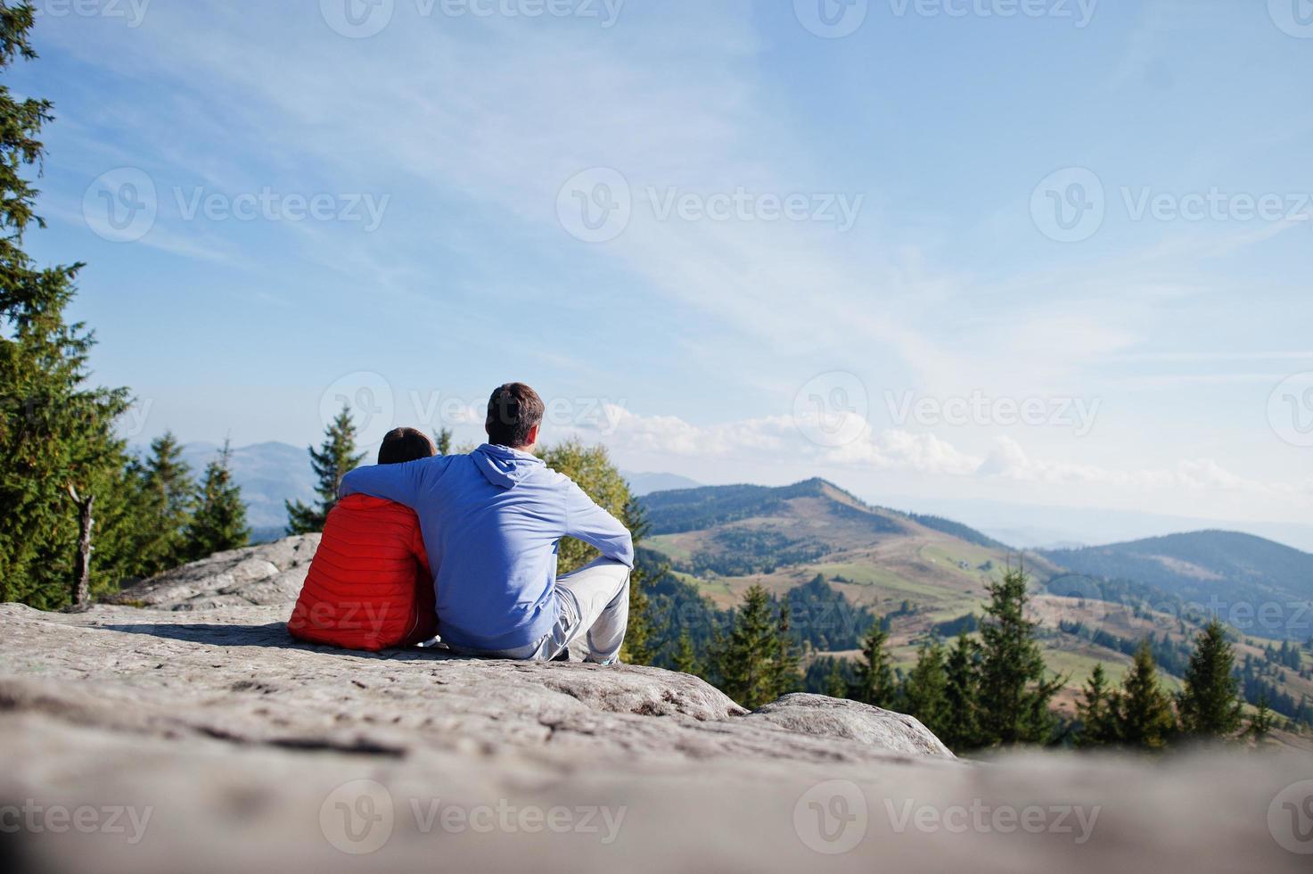 Father with son. Children hiking on beautiful day in mountains, resting on rock and admire amazing view to mountain peaks. Active family vacation leisure with kids.Outdoor fun and healthy activity. photo