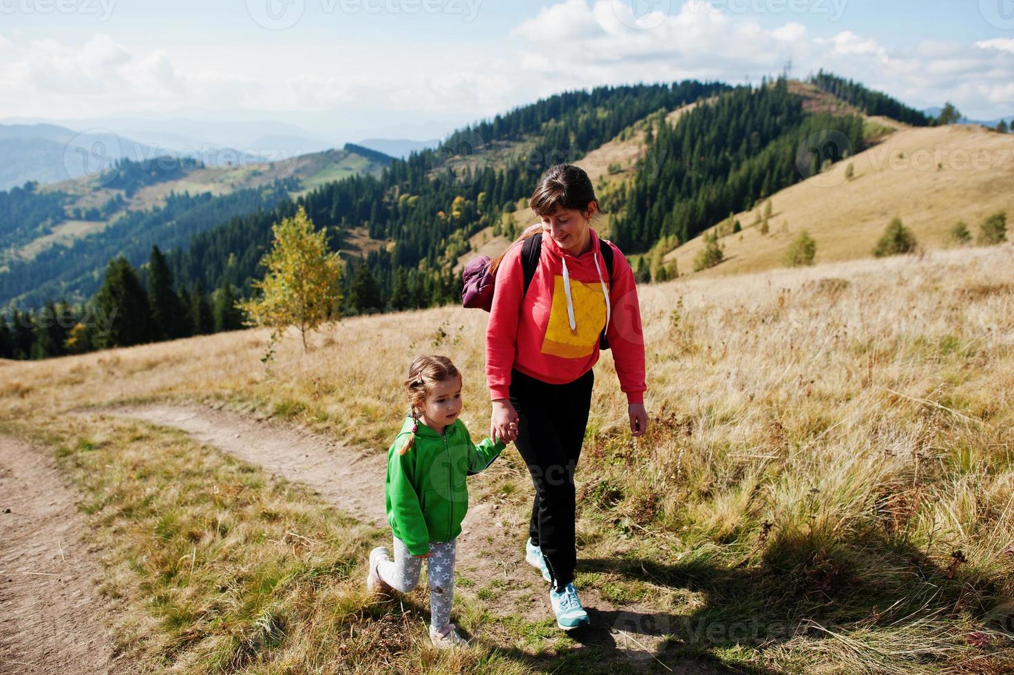 Mother and daughter hiking in the mountains.The concept of family travel, adventure, and tourism. Lifestyle autumn vacations outdoor. photo