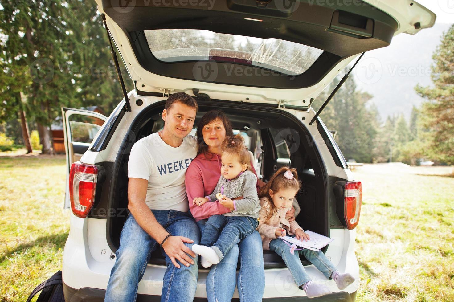 Family with two baby girls at vehicle interior. Children in trunk. Traveling by car in the mountains, atmosphere concept. photo