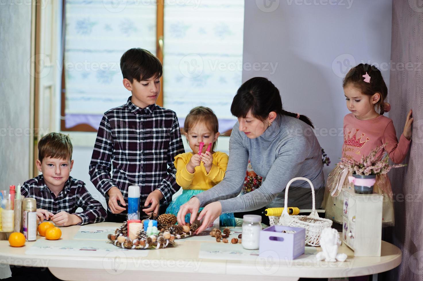 madre con cuatro hijos hace una corona para la víspera de navidad y la decoración artesanal. celebración de Año Nuevo. foto