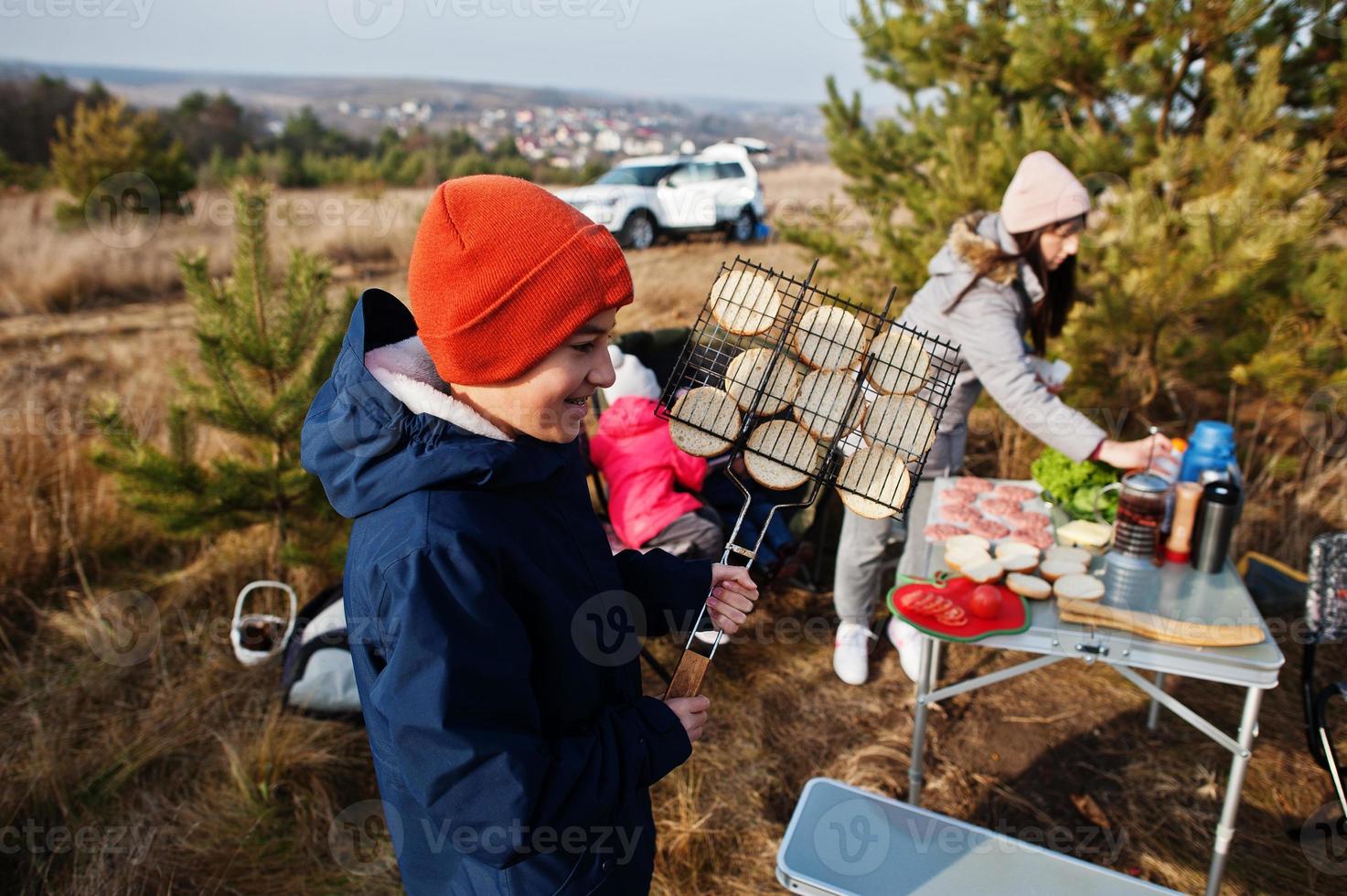 Family barbecuing on a deck in the pine forest. Bbq day with grill. photo