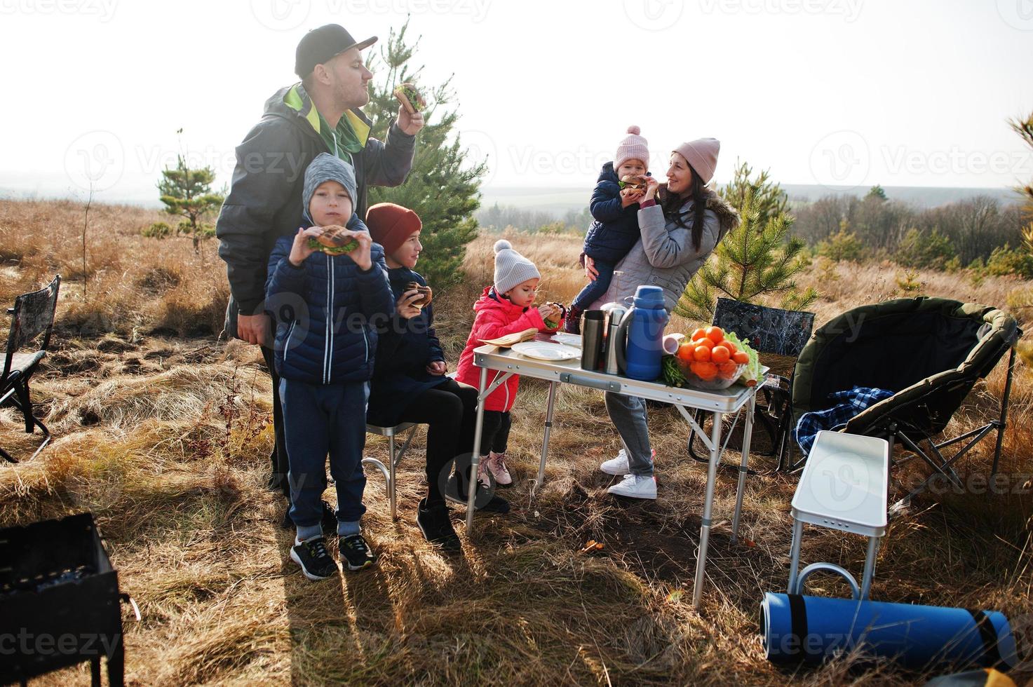 Family barbecuing on a deck in the pine forest. Bbq day with grill. photo