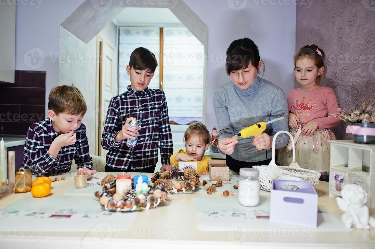 madre con cuatro hijos hace una corona para la víspera de navidad y la decoración artesanal. celebración de Año Nuevo. foto