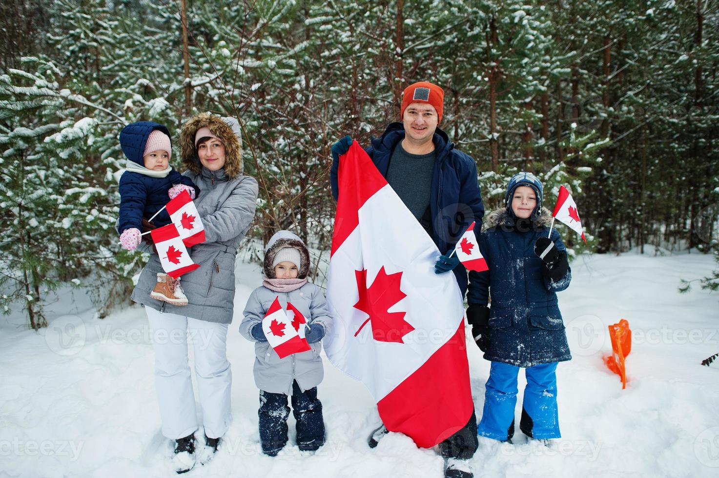 Family holding flag of Canada on winter landscape. photo