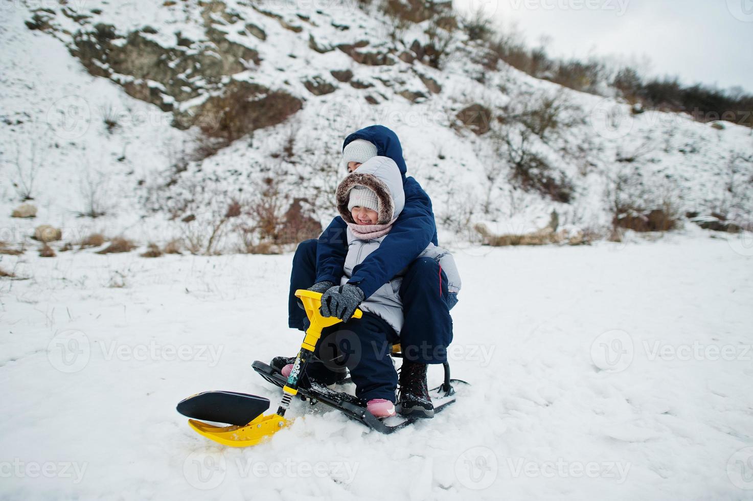 hermano y hermana disfrutan de un paseo en trineo. trineo infantil. niño montando un trineo en invierno. foto