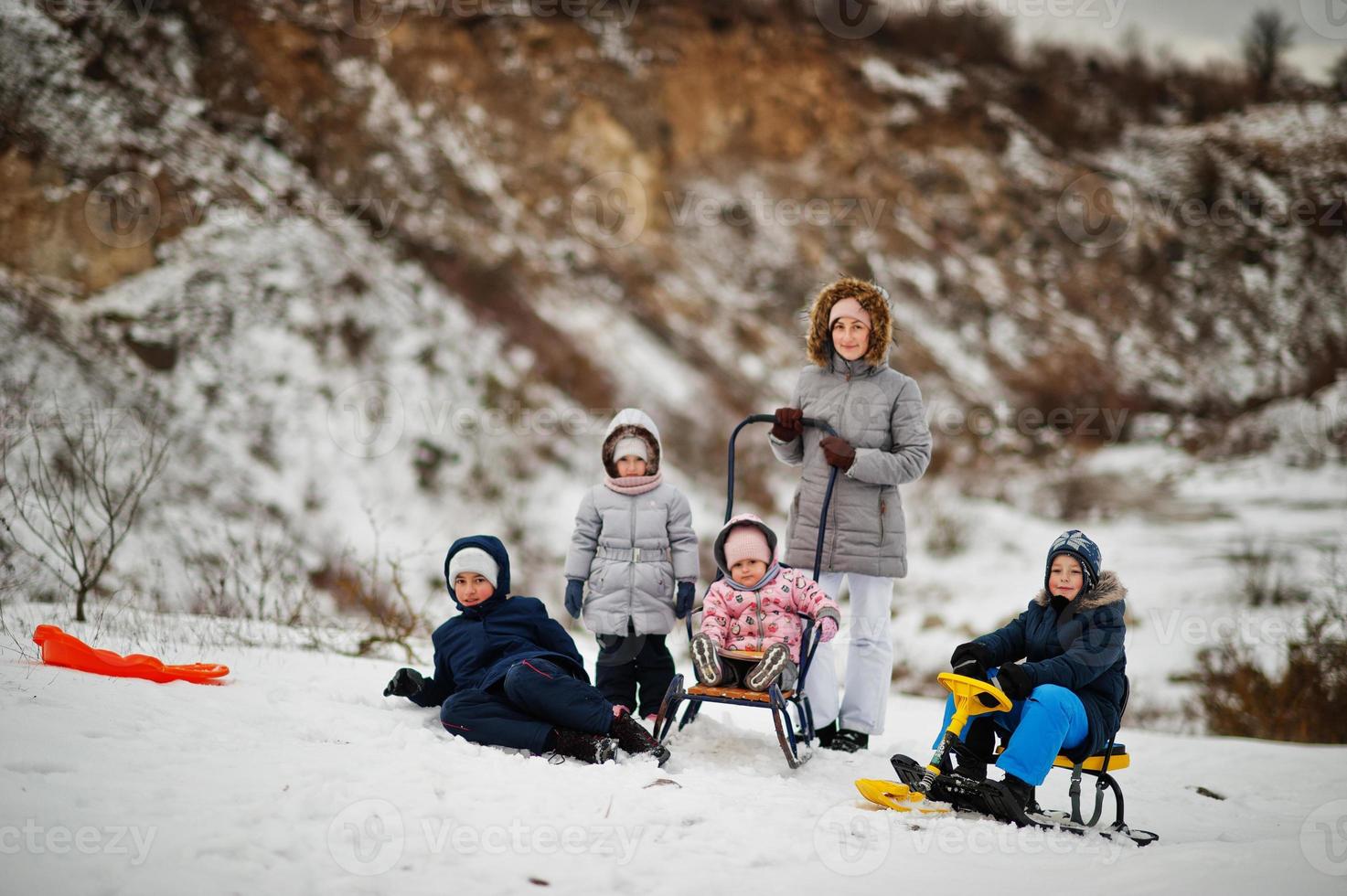 Family plays and sleigh rides in winter outdoor, mother and children having fun. photo
