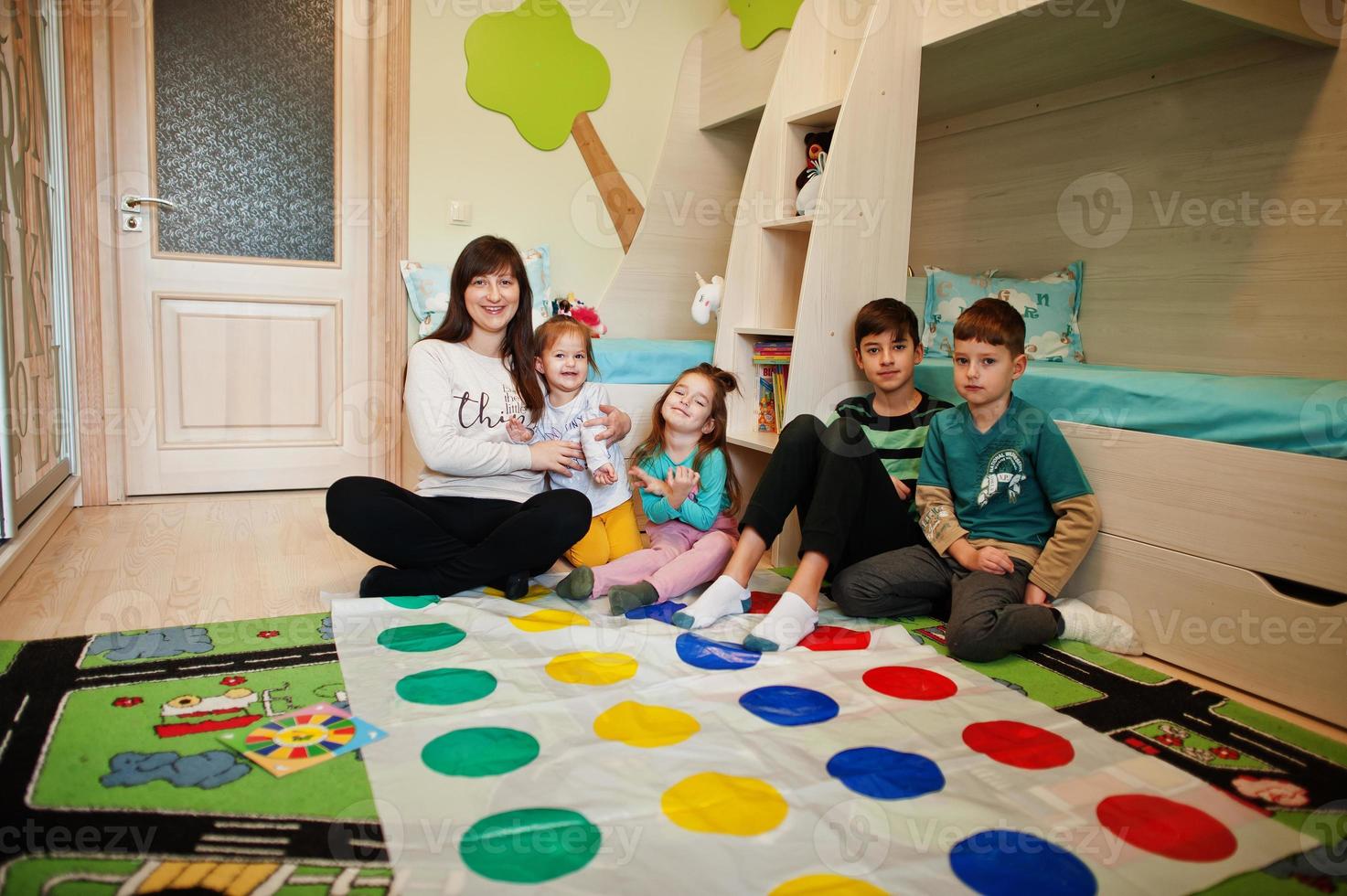 familia feliz divirtiéndose juntos, cuatro hijos y madre jugando al juego de tornado en casa. foto