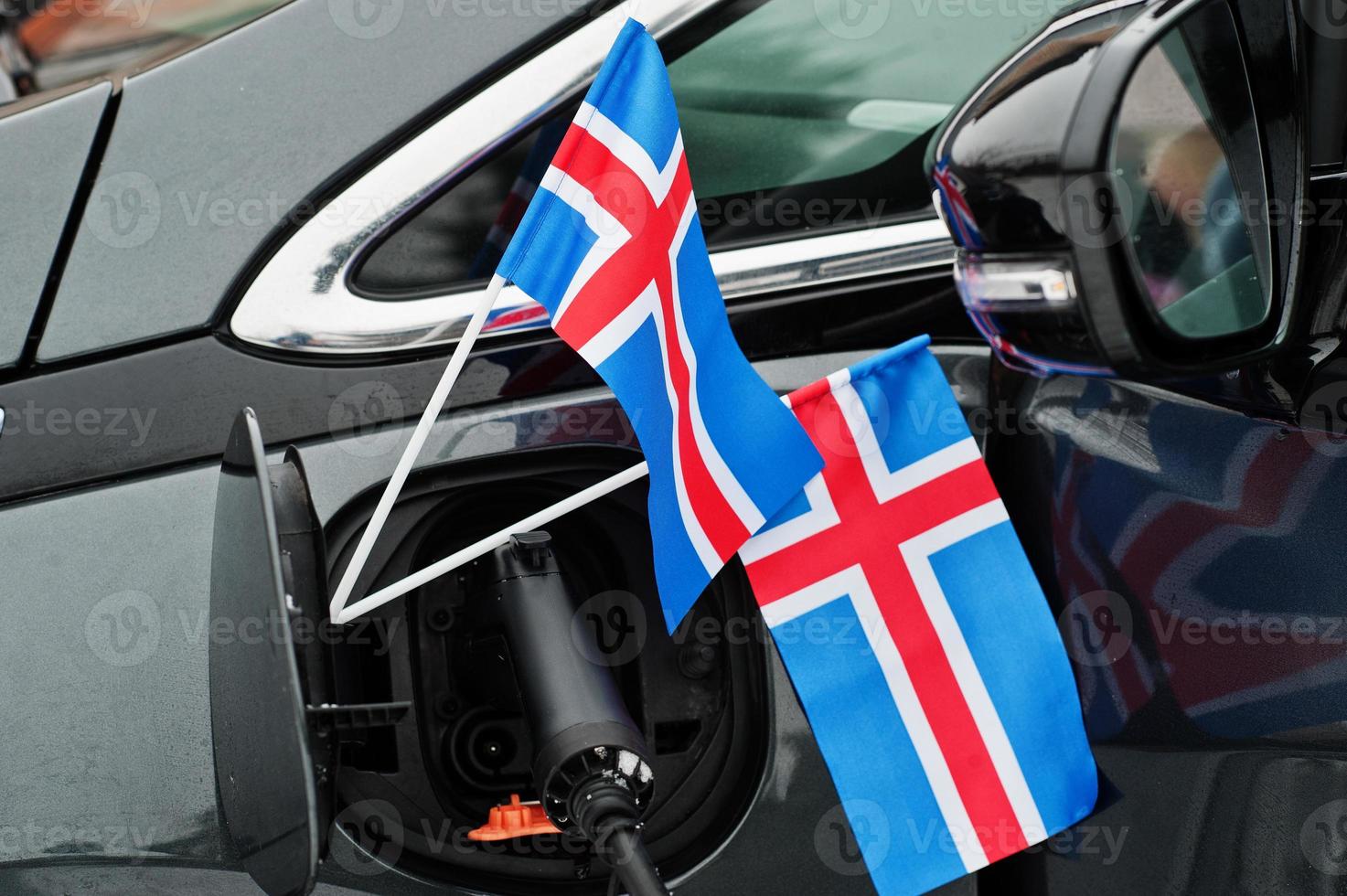 Iceland flag ecological car concept. Plugging a power supplier, charging modern automobile. photo