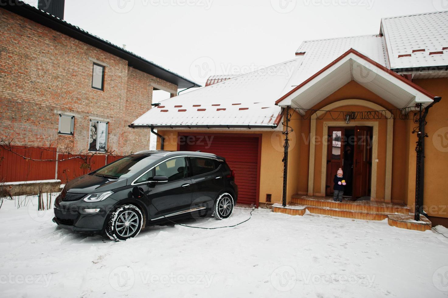 carga de coche eléctrico en el patio de la casa en invierno. foto