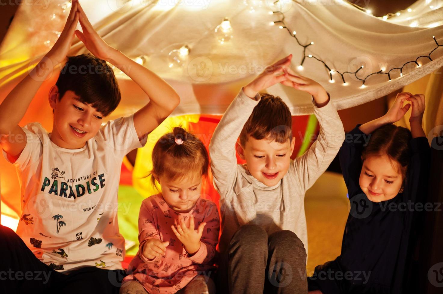 Playing kids in tent at night home. Hygge mood. photo