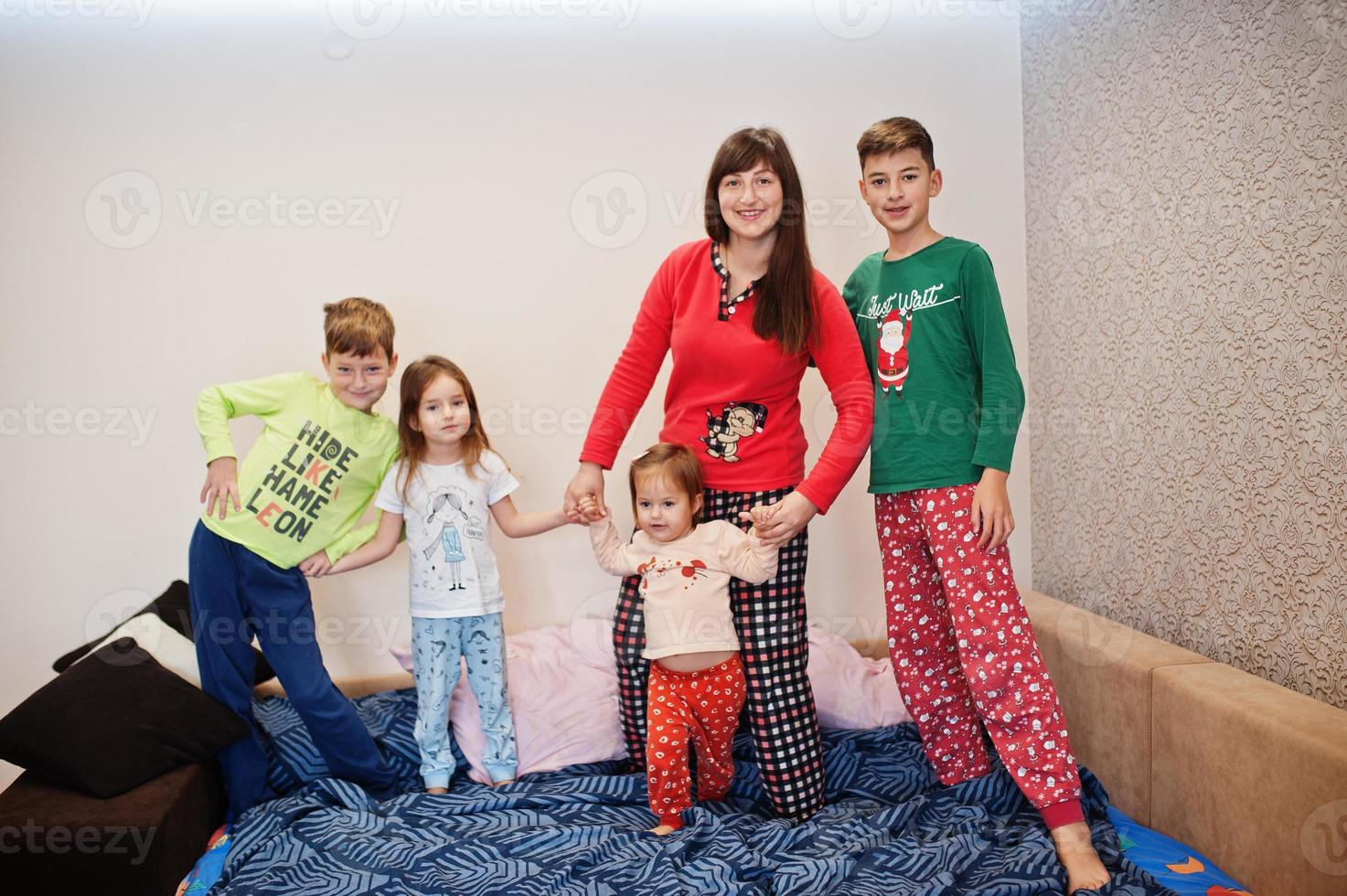 Happy big family is having fun together in bedroom. Large family morning concept. Mother with four kids wear pajamas in bed at home. photo