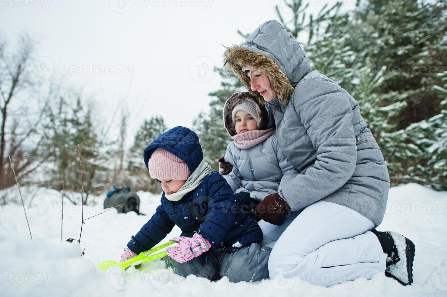 Mother with two baby girl daughters in winter nature. Outdoors in snow. photo